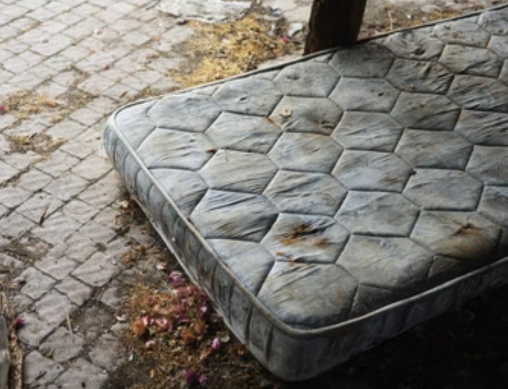 Colchón sucio y deteriorado tirado en la calle, mostrando el resultado del abandono y la falta de higiene.