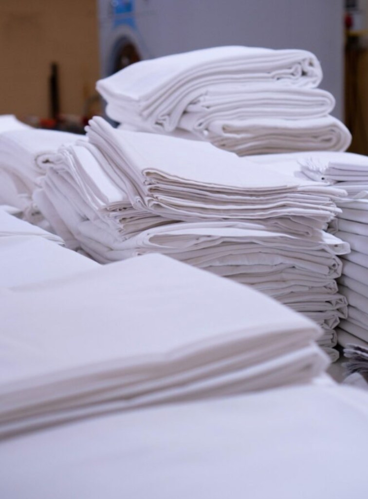 Manteles blancos recién lavados y doblados en lavandería industrial en Lumbrales